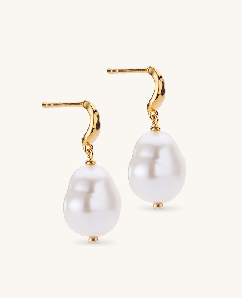 Gold earrings with large white pearls on a white background