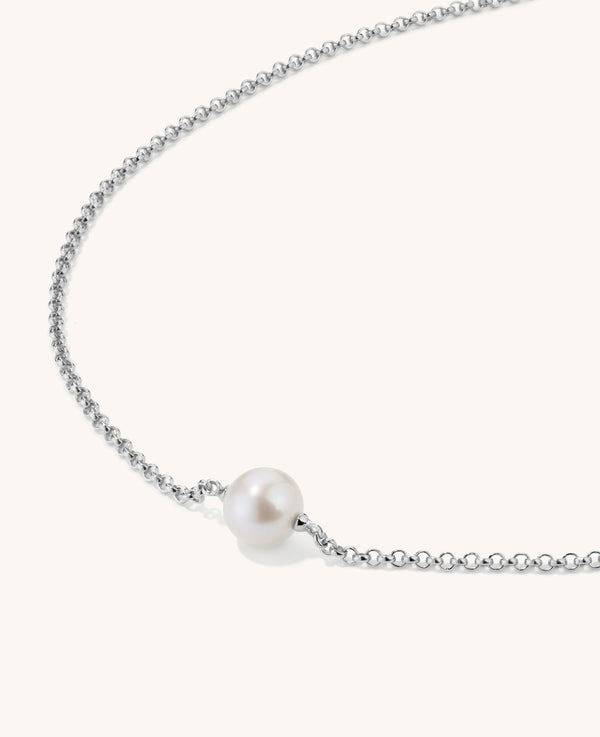 Small single pearl necklace on silver chain on white background