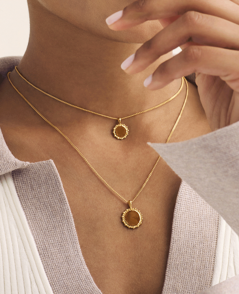 Custom gold vermeil initial letter necklace on model, layered with medium engraved name necklace, both in gold.