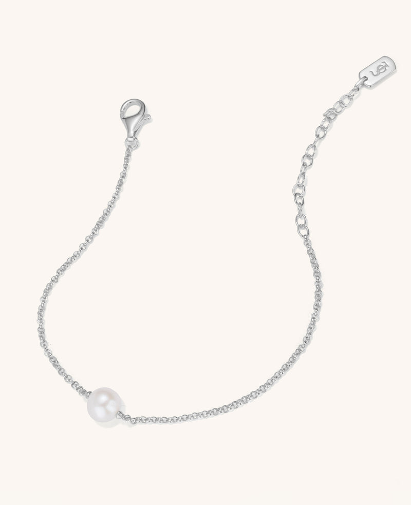 Silver bracelet with a single pearl on a light gray background