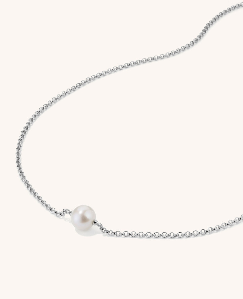 Pearl necklace on a thin chain against a white background