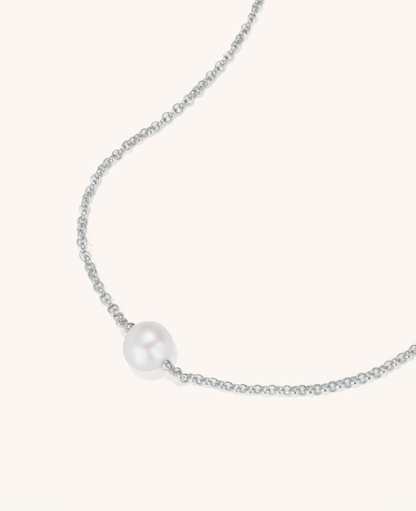 Pearl necklace on a thin chain against a white background
