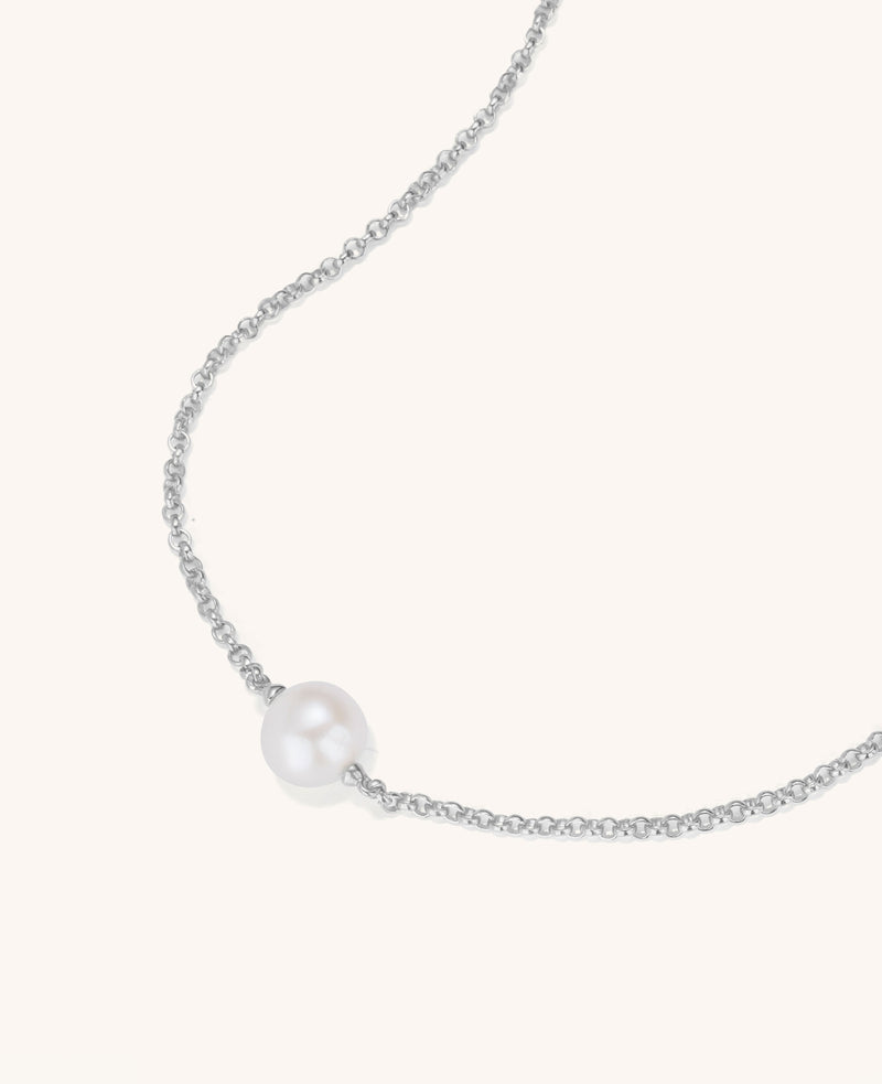 Pearl necklace on a thin chain against a white background